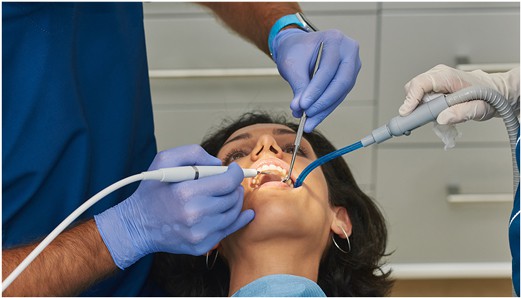 Female patient undergoing periodontic treatment by a Dentist and Dental Assistant at 4SquareDentistry