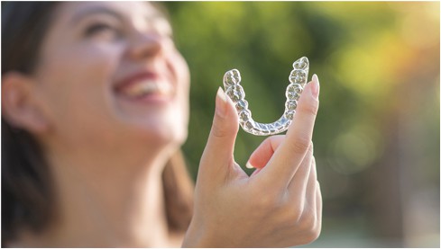 A girl showing clear aligners in hand at 4 sqaure dentisry.
