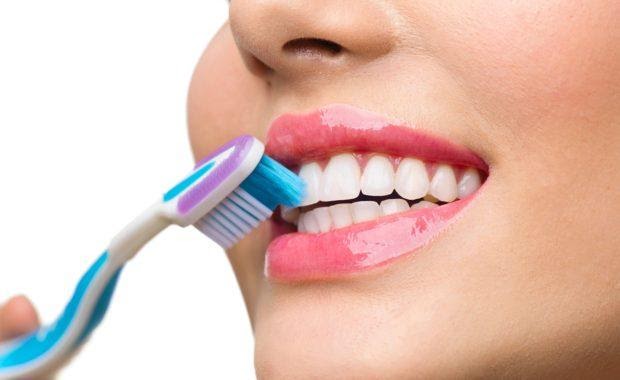 Closeup of a woman brushing her teeth while holding a toothbrush