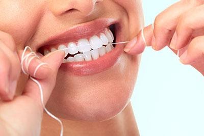 Closeup view of a female flossing her teeth with a dental floss