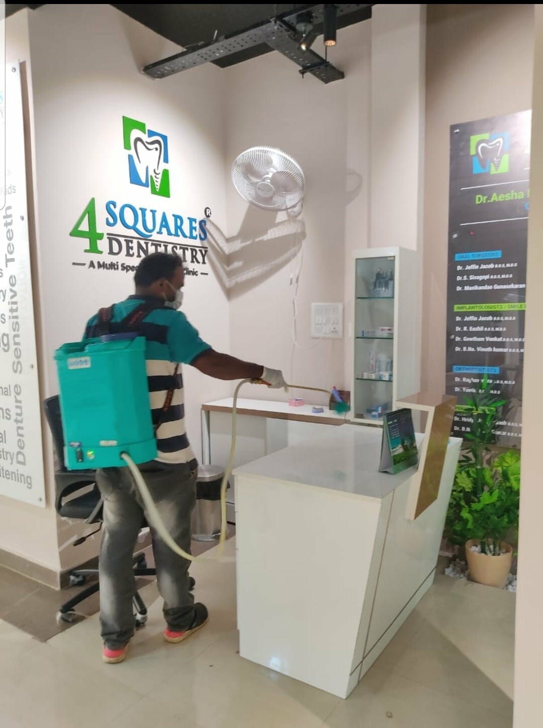 Sanitation worker disinfects the 4 Squares dental clinic's front desk in Gowrivakkam